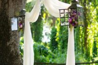 11 ethereal fabric hung as an arch, lanterns with flowers and a glam crystal chandelier for a wedding ceremony