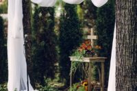 12 branches decorated with airy fabric, an altar with a cross and some blooms