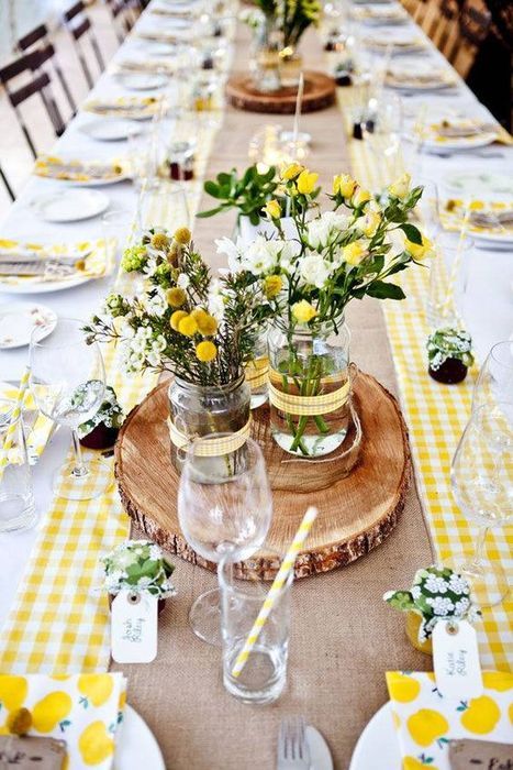 a bold rustic table setting with a checked yellow runner, wood slices and bold yellow blooms for the centerpiece