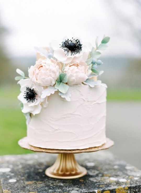 a simple rustic wedding cake with textural buttercream and some blooms on top