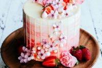 13 a tender watercolor pink and coral wedding cake with cream drip, cherry blossom and cut strawberries on top and sides