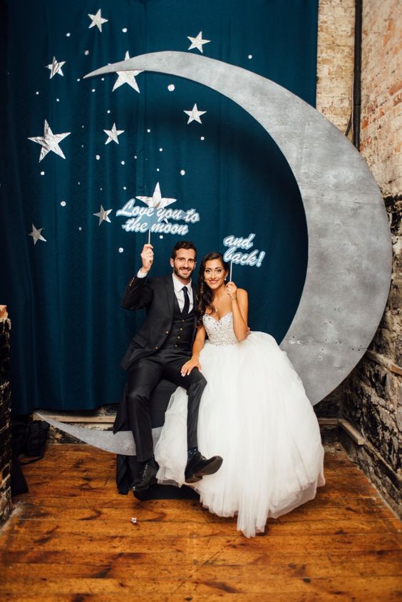 a cute photo booth setting with a crescent moon and stars and matching props for a wedding
