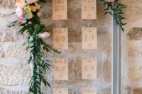 15 a frame with mesh and a seating chart, lush greenery garlands and large blooms on top
