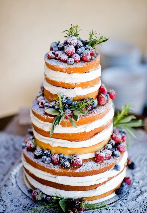 a naked wedding cake with fresh greenery and sugared berries on top is ideal for a rustic wedding
