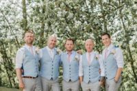 15 groomsmen wearing pink ties and blue vests with grey pants for a summer feel