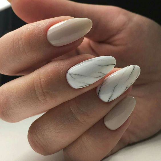 creamy nails and a couple of white marble accent nails for a chic and bold touch
