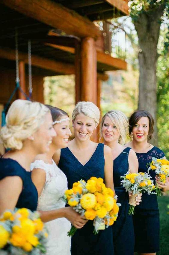 bridesmaids in navy dresses and holding yellow bouquets is a very bold and chic combo to go for