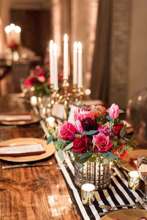 a glam bridal shower table with a striped runner, candles and bold floral centerpieces
