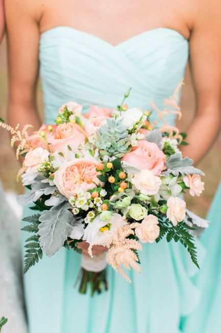 a bridesmaid wearing a strapless mint dress and a peachy pink and pale grey bouquet
