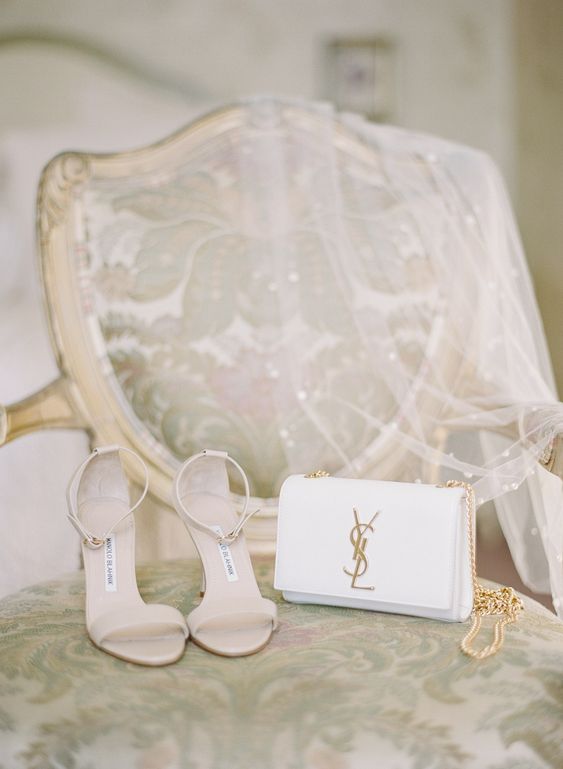 a white Yves Saint Lauren clutch with gold detailing can be used after the wedding, too