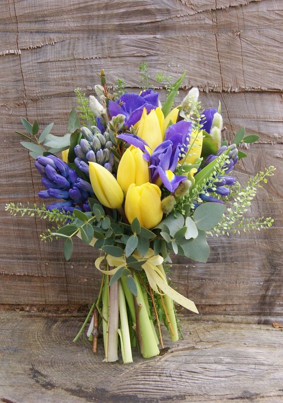a bridal bouquet of yellow tulips, purple iris, green thlaspi, blue hyacinth and pussy willow