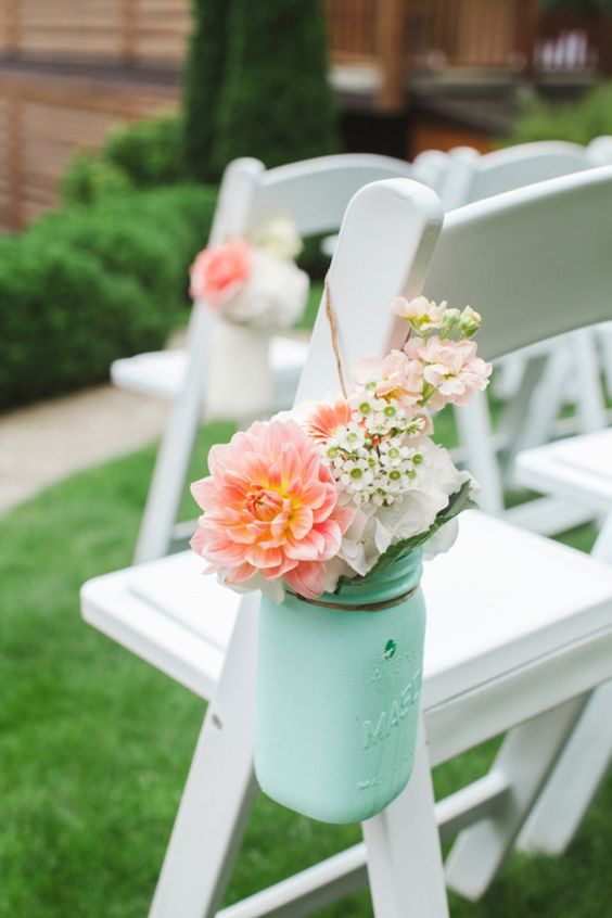 a ceremony space chair with a mint jar and peachy pink flowers in it