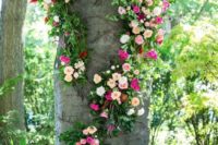 26 a tree wrapped with bold pink, blush and ivory blooms and greenery for a wedding ceremony