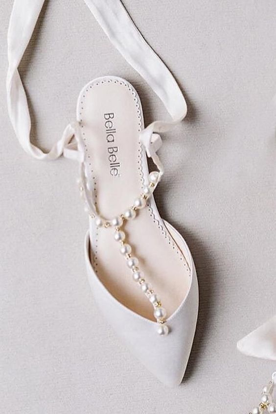 White flat mules with T straps and pearls plus ribbons are amazing for a chic and glam bridal look