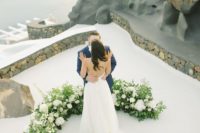 02 a chic and lush wedding altar with greenery and white blooms on high roof on Santorini for a wow look