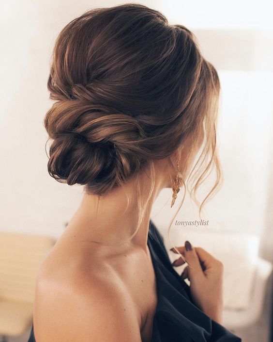 a chic twisted low bun with a small bump and some locks down for a timelessly romantic look