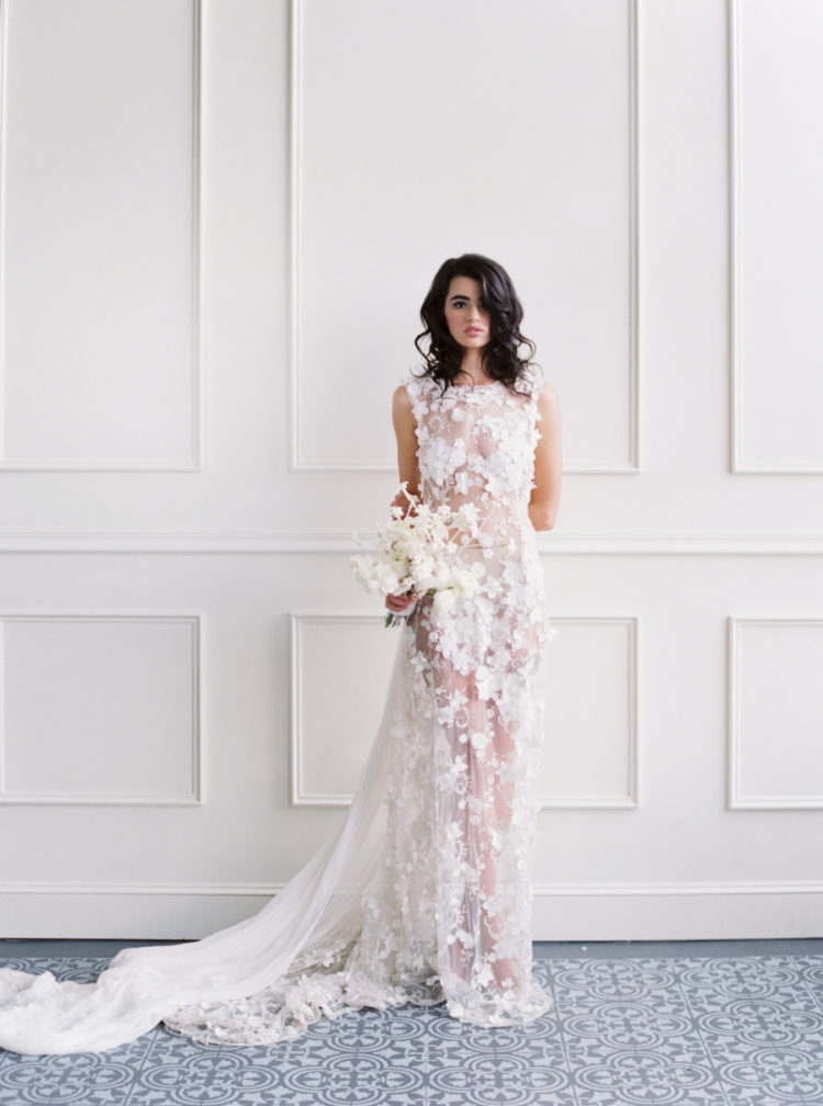 The bride was wearing a stunning sheer wedding dress with no sleeves, fully covered with white floral appliques