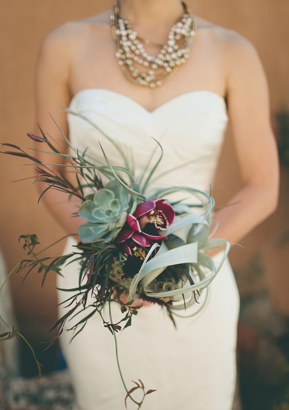 a gorgeous wedding bouquet with an air plant, a succulent, herbs and fuchsia blooms for a statement