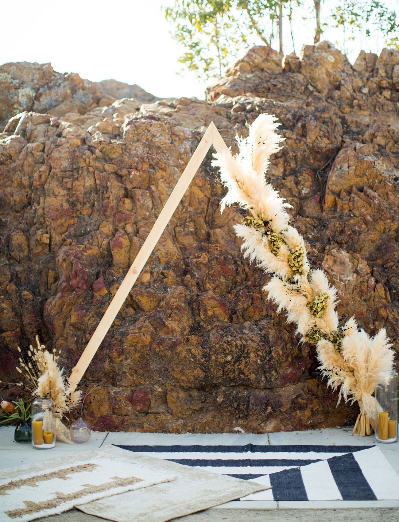 The wedding arch was triangle, with greenery, candles and pampas grass