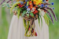 05 a colorful boho ethnic wedidng bouquet with orange, yellow blooms, blue thistles, lisianthus and woven ribbons
