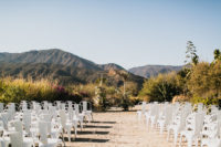 06 The wedding ceremony space was done with a boho textural arch and white chairs