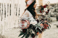 06 a boho bride with a lush bouquet and a hat decorated with blooms and cacti