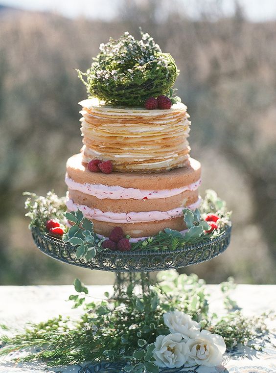 a naked partly pancake wedding cake with raspberries decorated with greenery is a catchy idea