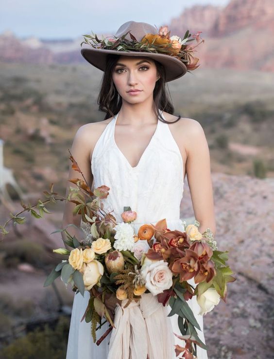 a brown hat decorated with flowers and greenery that match the bridal bouquet