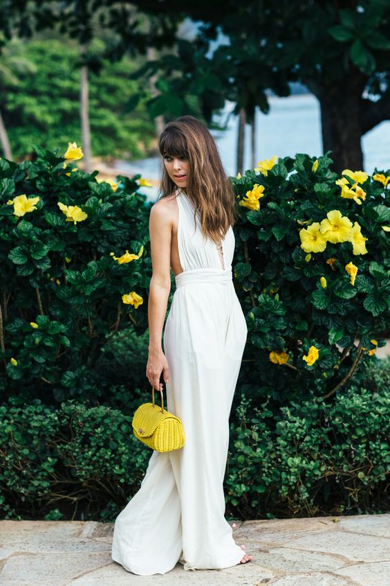 a white fitting plunging neckline jumpsuit with culottes and a neone yellow little bag for a wow effect