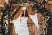 09 a boho bride wearing a boho lace wedding dress with bell sleeves and a white hat