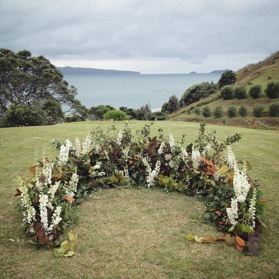 a textural fall wedding altar with white blooms, much foliage and herbs and dark leaves adds interest and dimension