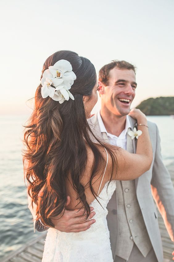 a wavy half updo with dimension and white orchids for a tropical beach bride