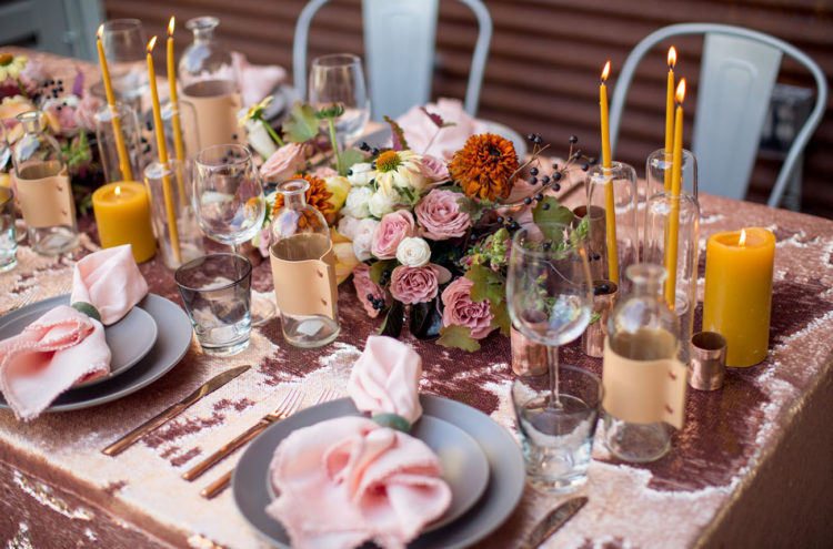 The wedding tablescape was done with pink sequins, pink and rust blooms, mustard candles and grey plates