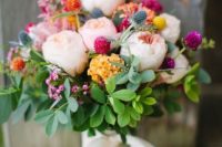 10 a gorgeous colorful bouquet with blush peonies, greenery, blue thistles and bold orange, yellow and pink clover