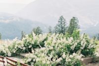 10 a very lush greenery and white bloom wedding altar up the steps with a cool mountain backdrop view