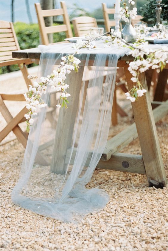 a sheer tulle light blue table runner with some blooming branches over it for a natural feel