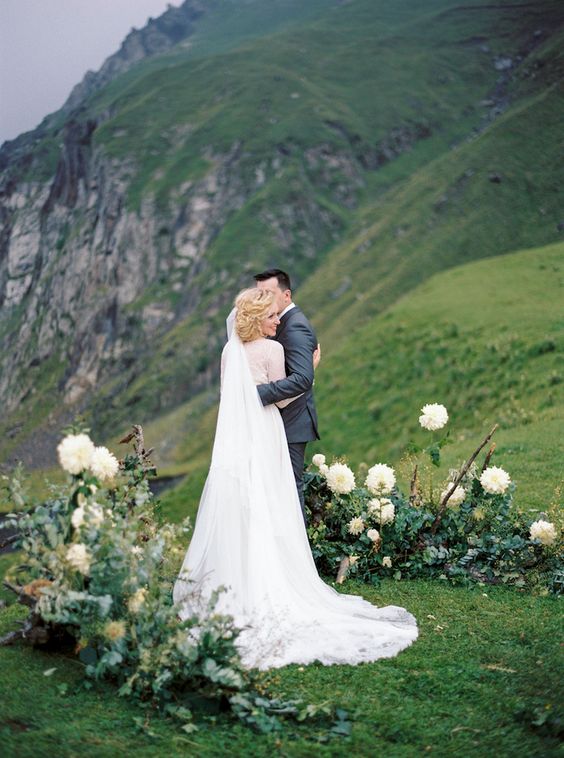 an organic greenery and white blooms outdoor wedding altar helps to enjoy the highlands around