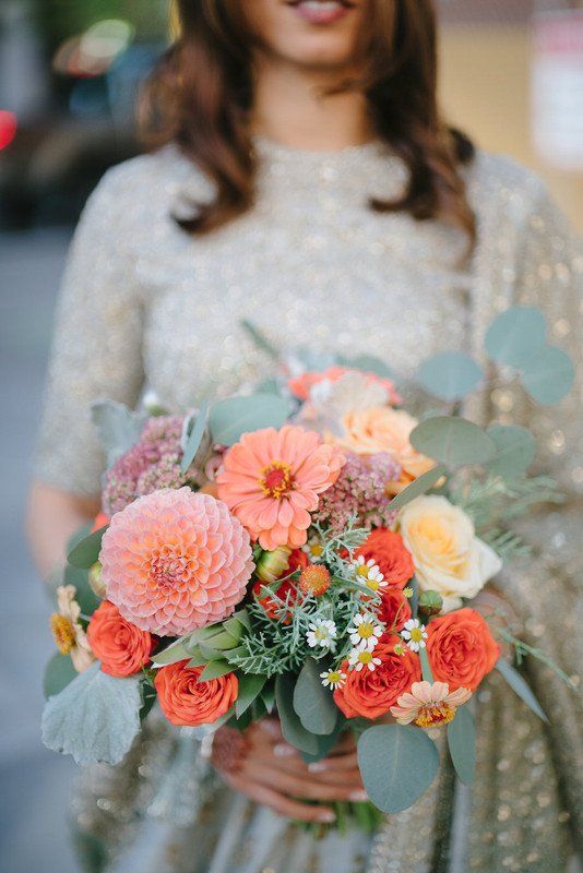a peach and coral wedding bouquet with dahlias, roses and muted greenery