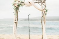 12 a rustic beach wedding arch with airy fabric, white and peachy blooms and eucalyptus