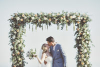 13 The wedding arch was mad eof greenery and peachy blooms, and th esea was the backdrop