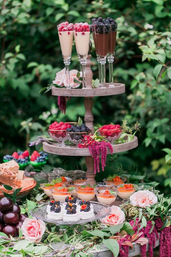 gorgeous desserts, cupcakes, berries and souffle served on a stand with flowers and greenery garlands to give it a garden feel