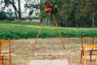 15 a triangle wedding arbow topped with lush cascading greenery and bold blooms in burgundy and orange for a fall wedding