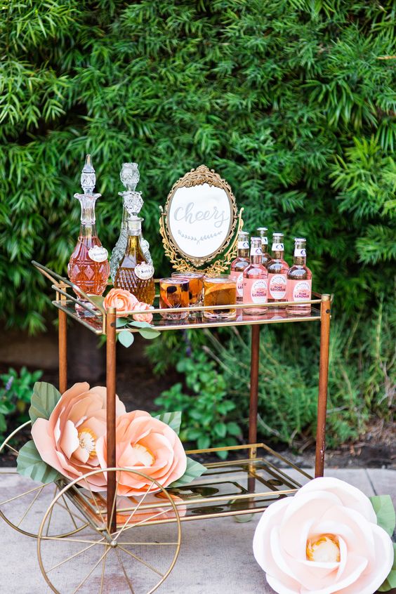 an elegant bar cart with oversized paper flowers and lots of drink served looks very refined and chic