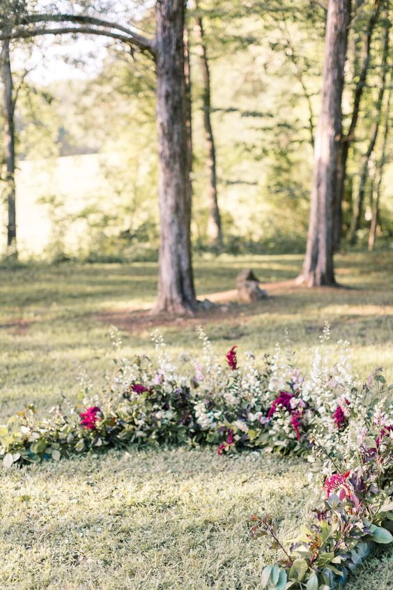 a greenery, herbs and plum-colored blooms woodland wedding arch looks very natural as if plants are growing here
