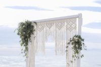 17 a marcrame wedding arch with greenery and white blooms for a beach boho wedding