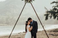 17 a metal triangle wedding arch with greenery and blooms on each corner of the triangle