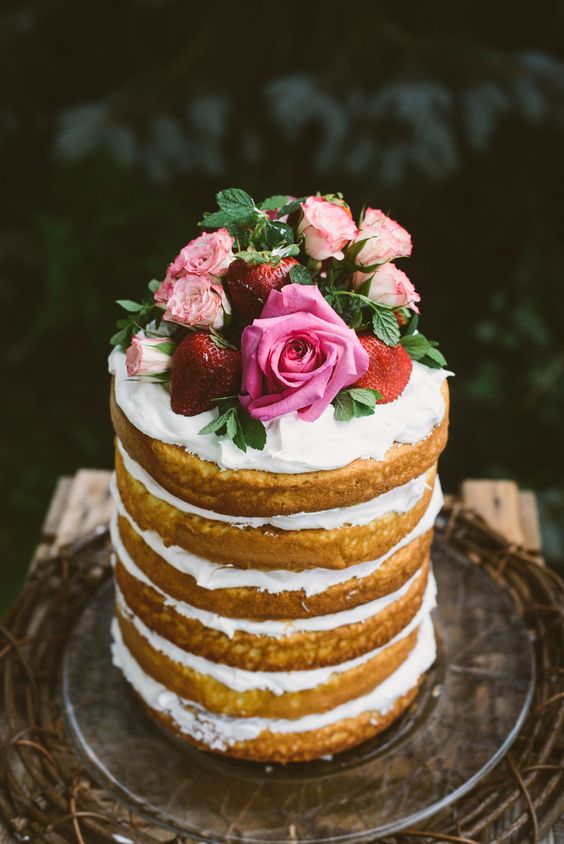a gorgeous tall naked cake with whipped cream, fresh strawberries and pink roses on top for a garden bridal shower