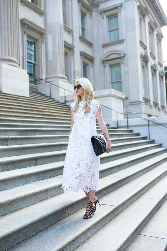 a loose white lace midi dress with cap sleeves and a high neckline, black laser cut shoes and a large black clutch
