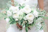 20 a lush all-white wedding bouquet with greenery and neutral ribbons hanging down is a timeless option