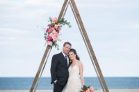 20 a romantic coastal wedding arch with bright blooms and greenery plus glass geometric candle lanterns